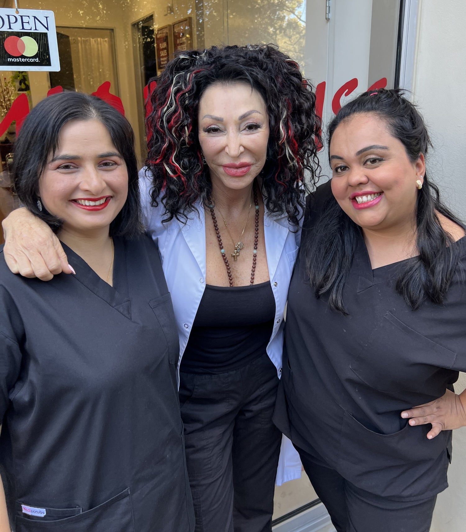 Reshma, Sandra, Anushka standing in front of the Miami Kiss shopfront window smiling for the camera